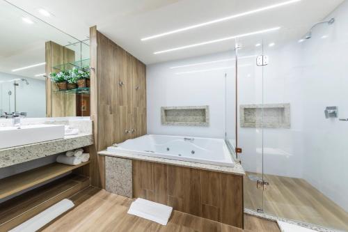a bathroom with a large tub and a shower at Hotel Thomasi Express - Londrina in Londrina