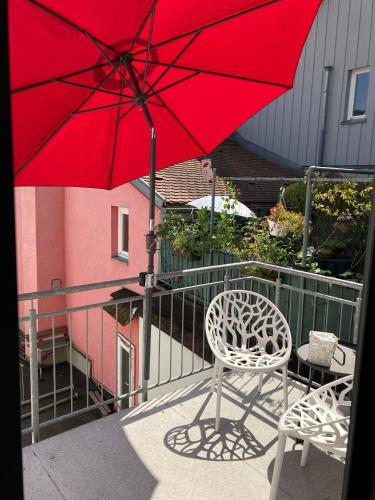 a red umbrella and a chair on a balcony at Altstadtliebe Konstanz - zentral & modern in Konstanz