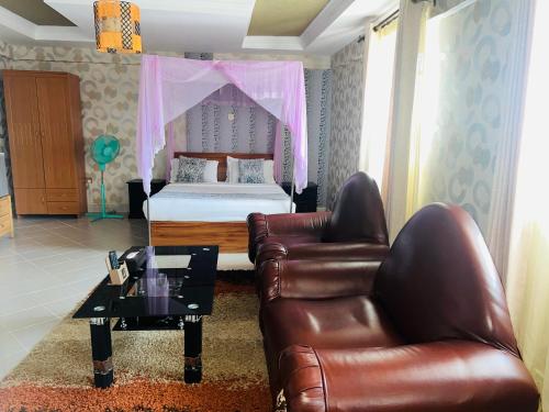 HOTEL NOKRAS (K) LIMITED في Murangʼa: غرفة نوم بسرير واريكة وطاولة