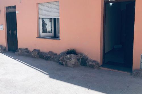 a pink building with a window and rocks next to it at Il Bed and Breakfast al Centro in Castelsardo