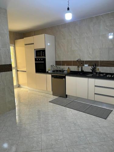 a large kitchen with white cabinets and appliances at Entre Mer et Montagne in Tabarka