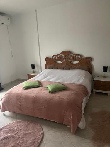 a bedroom with a large bed with two green pillows at Entre Mer et Montagne in Tabarka