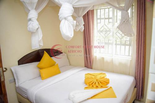 a bed with yellow and white pillows and a window at Kericho Pride Hotel in Kericho