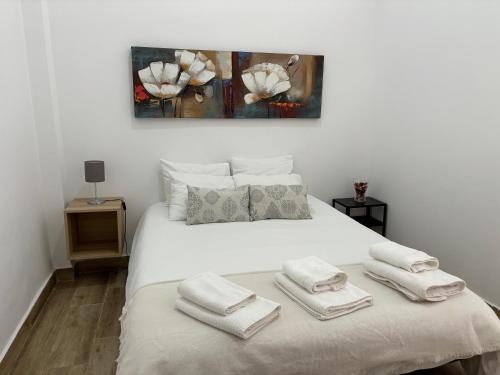 um quarto com uma cama branca e toalhas em Apartamento Cruz Roja A em Sevilha