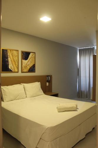 um quarto com uma cama grande e lençóis brancos em Marezzi Hotel Aracaju em Aracaju