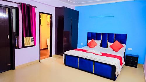 a blue bedroom with a bed with red pillows at Hotel Happy Residency-Sainik Farms in New Delhi