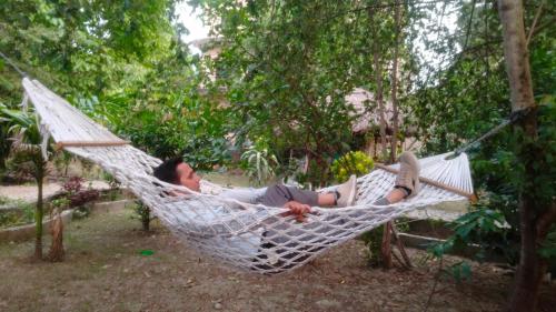 - un homme dormant dans un hamac dans un jardin dans l'établissement Hotel Tiger Tops Sauraha, à Sauraha