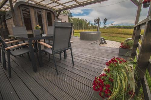 a wooden deck with a table and chairs and flowers at Purenes - Barrel shaped pod with hot tube in Sliseri