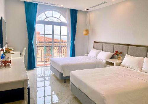 a hotel room with two beds and a window at Moonlight Hotel Phu Quoc in Phu Quoc