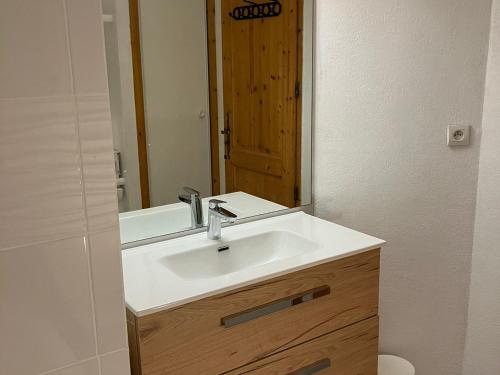 une salle de bain avec un lavabo blanc et un miroir dans l'établissement Appartement 3 pièces avec piscines, sauna et parking à Samoëns - FR-1-629-106, à Samoëns