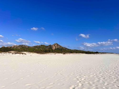 a white beach with a mountain in the background at Splendida villa unifamiliare Posada in Torpè