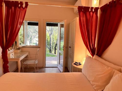 a bedroom with a bed with red curtains and a desk at Splendida villa unifamiliare Posada in Torpè