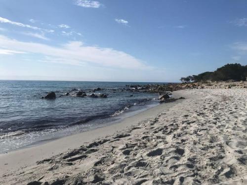 a beach with a bunch of rocks in the water at Splendida villa unifamiliare Posada in Torpè