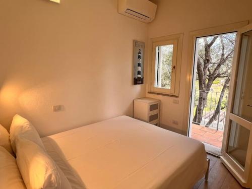 a bedroom with a white bed and a window at Splendida villa unifamiliare Posada in Torpè