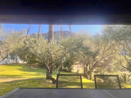 a window with a view of a field and trees at Splendida villa unifamiliare Posada in Torpè