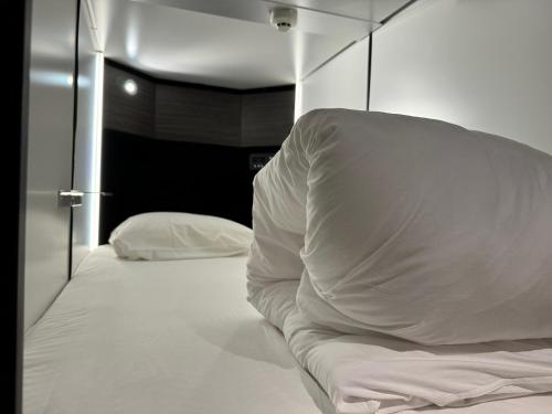 a bedroom with a white bed and a mirror at Capsule Hotel Suzumoriya in Tokyo