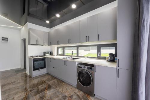 een keuken met witte kasten en een wasmachine en droger bij Jacuzzi & luxury house in Iaşi