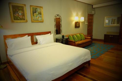 a bedroom with a large white bed and a couch at Ban Mai Vintage in Pak Chong
