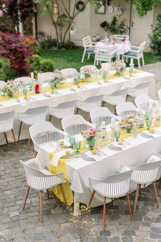 a group of tables with white chairs and flowers on them at La Fontaine in Hunedoara