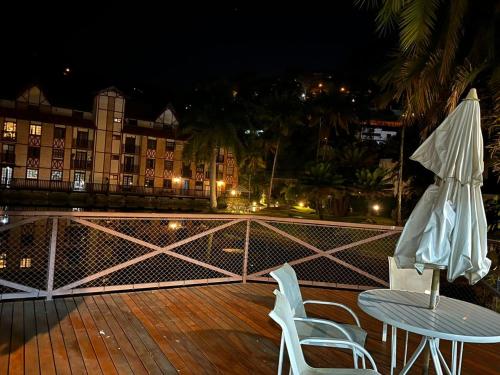 a patio with a table and chairs and an umbrella at Lagos de Itaipava in Bom Sucesso