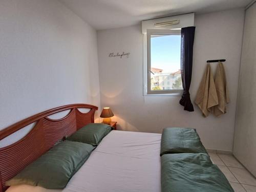 une chambre avec un lit avec des oreillers verts et une fenêtre dans l'établissement Les Calanques d'Azur, à Saint-Aygulf