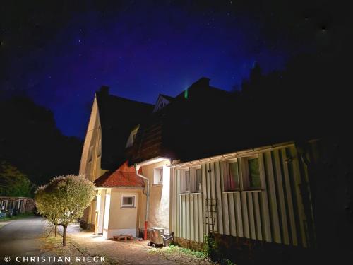 a house at night with a tree next to it at Klimaanlage, 5 Sterne Bahnhoftraum, Appartement "Waldliebe" 133qm, große Terrasse 70qm, QR Code scannen für virtuellen Rundgang, Premium Ausstattung in Braunfels