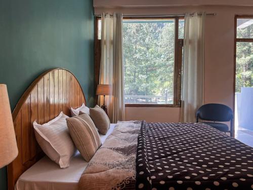 a bedroom with a bed with a large window at Madpackers Kasol Riverside - Katagla in Kasol