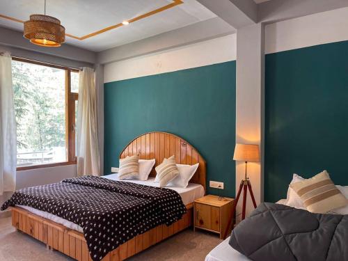 a bedroom with two beds and a blue wall at Madpackers Kasol Riverside - Katagla in Kasol