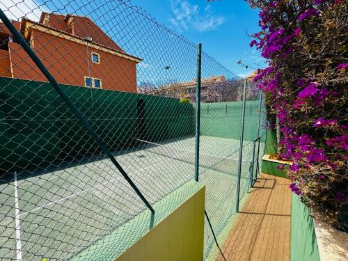 a tennis court with a net and some purple flowers at La Gavina Loft Xàbia in Jávea