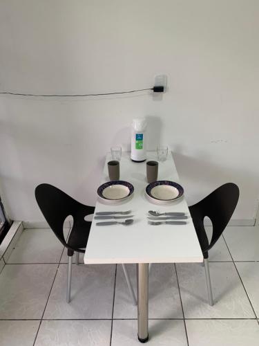 a white table with two chairs and plates on it at Apartamento grande para família ou amigos in Boa Vista
