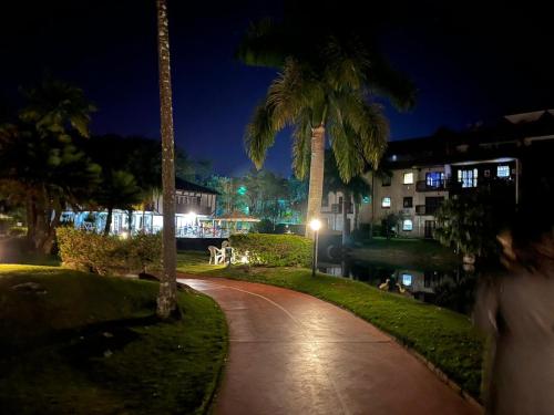 a walkway with palm trees and buildings at night at Lagos de Itaipava in Bom Sucesso