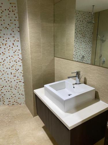 a bathroom with a white sink and a mirror at KLCC View by Regalia Dorms in Kuala Lumpur