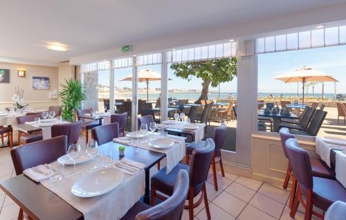 ein Restaurant mit Tischen und Stühlen und Meerblick in der Unterkunft Albatros in Quiberon