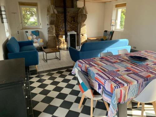 a living room with a table and blue chairs and a fireplace at Maison de Kermouster, juste avant le Paradis in Lézardrieux