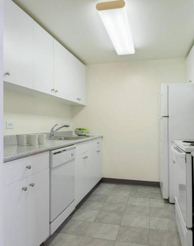 a kitchen with white cabinets and a white refrigerator at Beautiful Studio Apartment in NYC! in New York