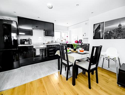 a kitchen with black and white appliances and a table and chairs at Charming London Home, Opp Arnos Grove Underground Station, Parking in New Southgate