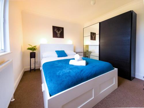 a bedroom with a bed with blue sheets and a mirror at Charming London Home, Opp Arnos Grove Underground Station, Parking in New Southgate