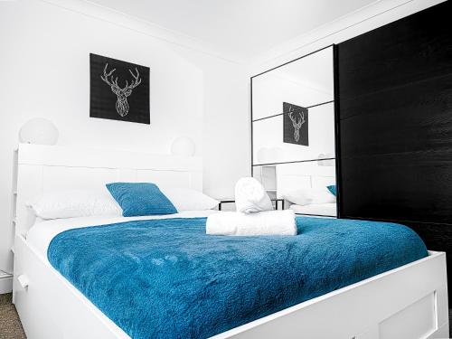 - une chambre blanche avec une couverture bleue sur un lit dans l'établissement Charming London Home, Opp Arnos Grove Underground Station, à New Southgate
