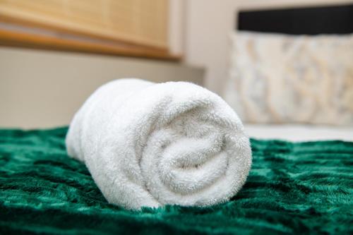 een witte handdoek op een groen bed bij Ushaka Waterfront Penthouse with Rooftop Jacuzzi in Durban