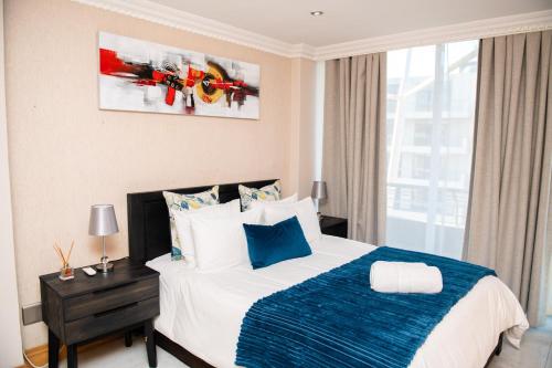 a bedroom with a bed with a blue and white blanket at Ushaka Waterfront Penthouse with Rooftop Jacuzzi in Durban