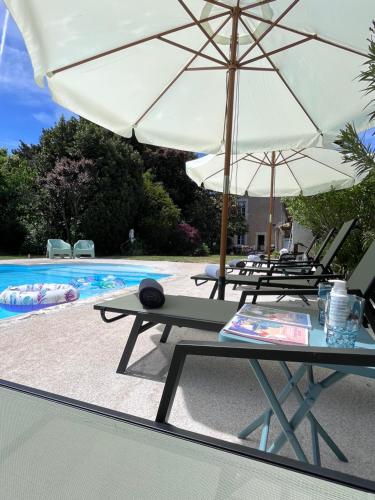 a group of tables and umbrellas next to a pool at Le Clos Gabrielle in Châtellerault