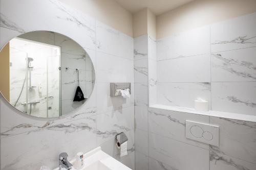Baño blanco con lavabo y espejo en Cit'Hotel Le Logis De Brou en Bourg-en-Bresse