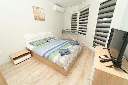 1 dormitorio con 1 cama y escritorio con TV en Слънце и море Бургас en Burgas
