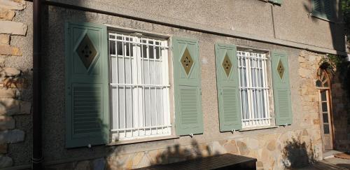 drie ramen met groene en witte luiken op een gebouw bij Appartamento Ibisco in Recco