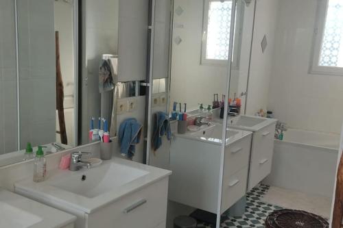 une salle de bain blanche avec deux lavabos et un miroir dans l'établissement Mon jardin secret, à Lunel