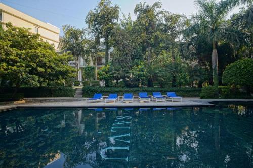 a swimming pool with blue lounge chairs next to a building at The Narayana Sanctuary - Luxe Poolside Suites by SALVUS in Rishīkesh