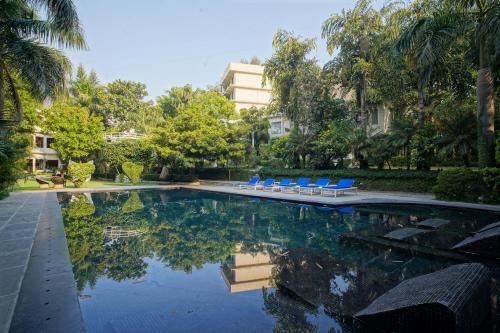 a swimming pool with blue chairs and a building at The Narayana Sanctuary - Luxe Poolside Suites by SALVUS in Rishīkesh