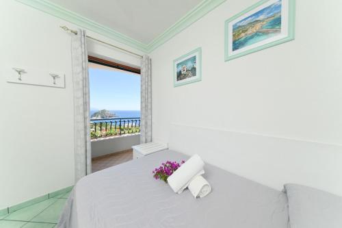 biała sypialnia z łóżkiem z kwiatami w obiekcie Villa Eleonora, un angolo di Paradiso ad Ischia w mieście Ischia
