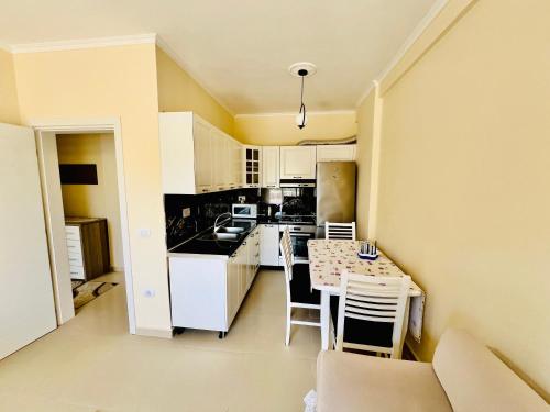 eine Küche mit weißen Schränken sowie einem Tisch und Stühlen in der Unterkunft N&E Apartment in Durres in Durrës