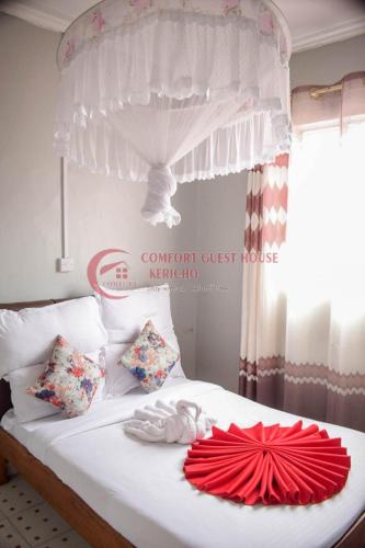 a white bed with a red fan on it at Heritage Villa Hotel & Accomodation in Kericho